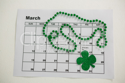 St. Patricks Day shamrock and beads kept on calendar