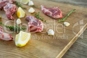Rib chops, herbs and lemon against wooden background