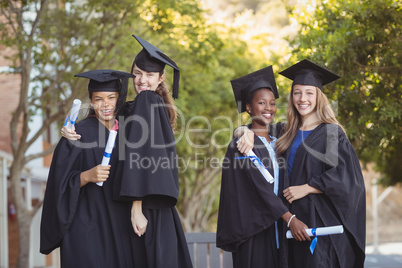 Portrait of graduate school kids standing with degree scroll in campus