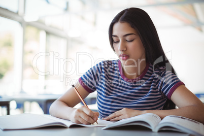 Attentive schoolgirl doing homework in classroom