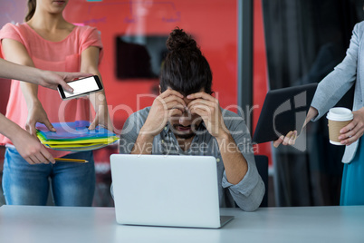 Colleagues with digital tablet and mobile phone talking to frustrated man