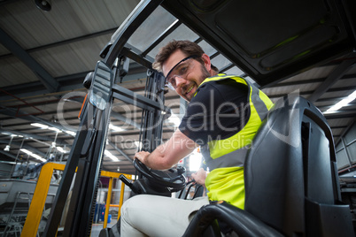 Portrait of smiling factory worker driving forklift