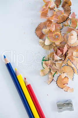 Colored shavings with colored pencils and sharpener on white background