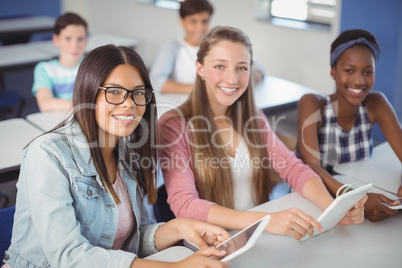 Students holding digital tablet in classroom