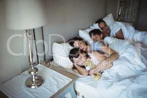 Parents and kids sleeping on bed