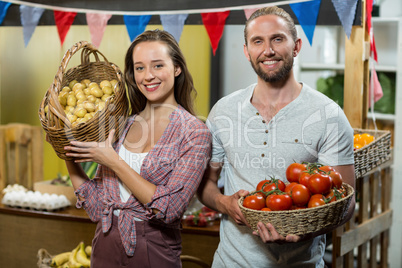 Woman and man vendors holding a basket of tomatoes and potatoes