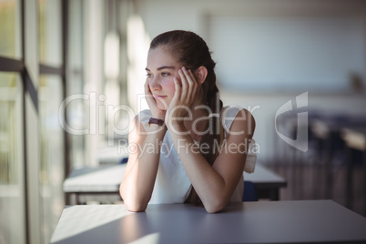 Thoughtful schoolgirl sitting in classroom