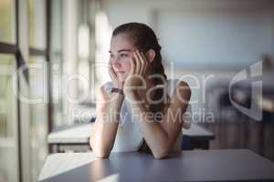 Thoughtful schoolgirl sitting in classroom