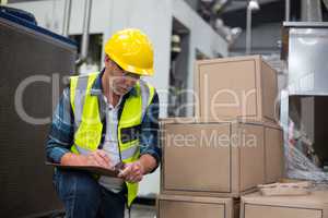 Male factory worker maintaining record on clipboard