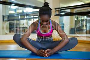 Fit woman doing stretching exercise on mat