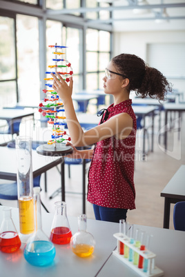 Attentive schoolgirl experimenting molecule model in laboratory