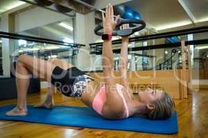 Fit woman exercising with pilates ring on mat