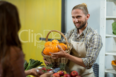 Smiling vendor offering oranges to the woman at the counter