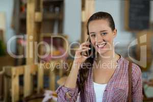 Portrait of smiling woman talking on mobile phone at counter