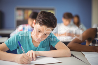 Attentive schoolboy studying in classroom