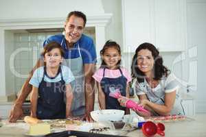 Portrait of happy family preparing cookies in kitchen
