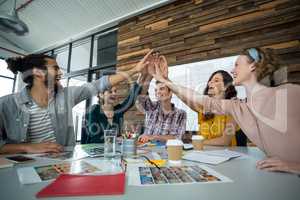 Graphic designers giving high five during meeting