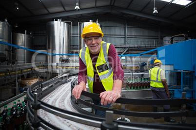 Smiling factory worker leaning on production line