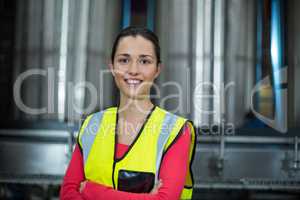Female factory worker standing with arms crossed at drinks production factory