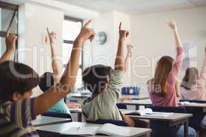 School kids raising hand in classroom