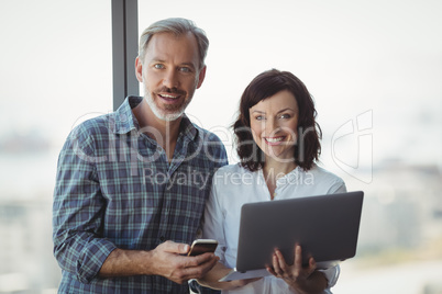 Portrait of executives using mobile phone and laptop