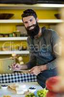 Portrait of salesman writing on clipboard at counter