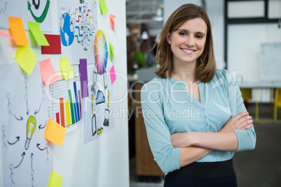 Female graphic designer standing with hands crossed in creative office