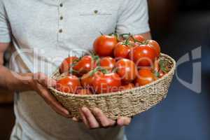 Vendor holding a basket of tomatoes