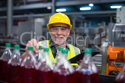 Male factory worker monitoring cold drink bottles