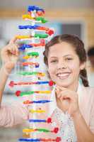 Portrait of happy schoolgirl experimenting molecule model in laboratory