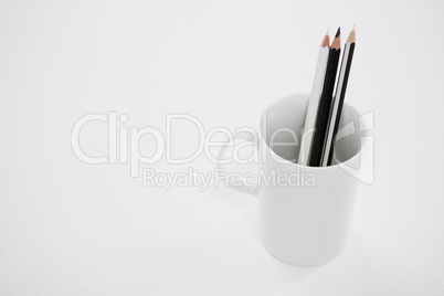 Black and white colored pencils kept in mug on white background