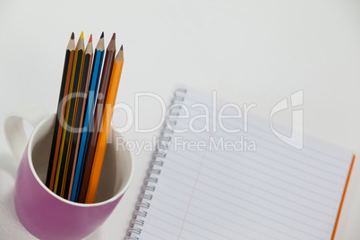 Colored pencils kept in cup and notepad