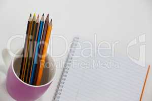 Colored pencils kept in cup and notepad