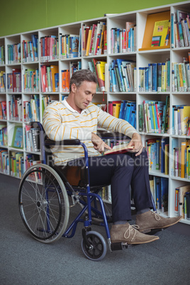 Attentive disabled school teacher reading book in library