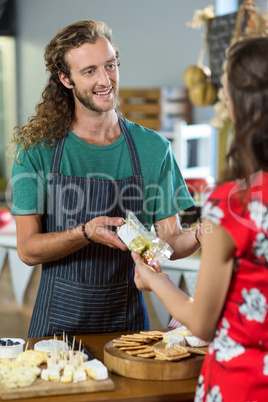 Smiling male staff giving parcel to woman at counter