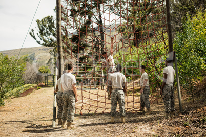 Military soldier climbing rope during obstacle course