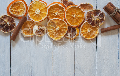 Dried round pieces of orange and lemon on a white wooden surface