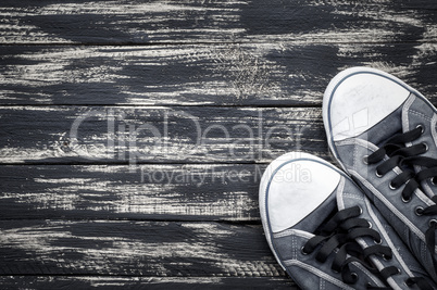 Shabby man's blue sneakers  on a wooden surface