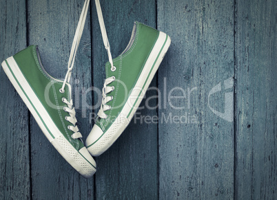 Green youth sneakers hanging on a nail