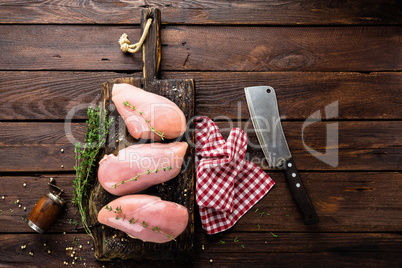 Raw chicken breasts fillets with thyme and spices on wooden cutting board on rustic background copy space directly above