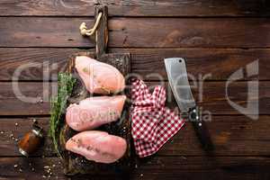 Raw chicken breasts fillets with thyme and spices on wooden cutting board on rustic background copy space directly above