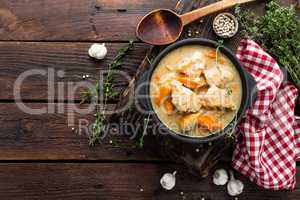 Meat stewed with carrots in sauce and spices in cast iron pan on dark wooden rustic background top view flat lay