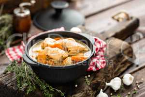 Meat stewed with carrots in sauce and spices in cast iron pan on dark wooden rustic background top view flat lay