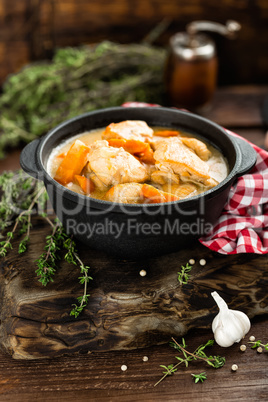 Meat stewed with carrots in sauce and spices in cast iron pan on dark wooden rustic background top view flat lay