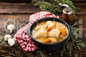 Meat stewed with carrots in sauce and spices in cast iron pan on dark wooden rustic background top view flat lay