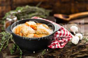 Meat stewed with carrots in sauce and spices in cast iron pan on dark wooden rustic background top view flat lay