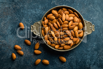 Almond nuts on dark background directly above copy space flat lay