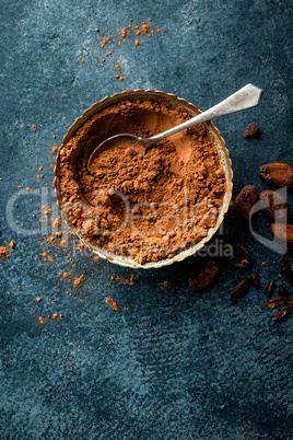 Cocoa powder and cacao beans on dark background, top view