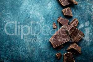 Dark chocolate pieces crushed on a dark background, view from above