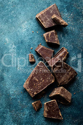 Dark chocolate pieces crushed on a dark background, view from above